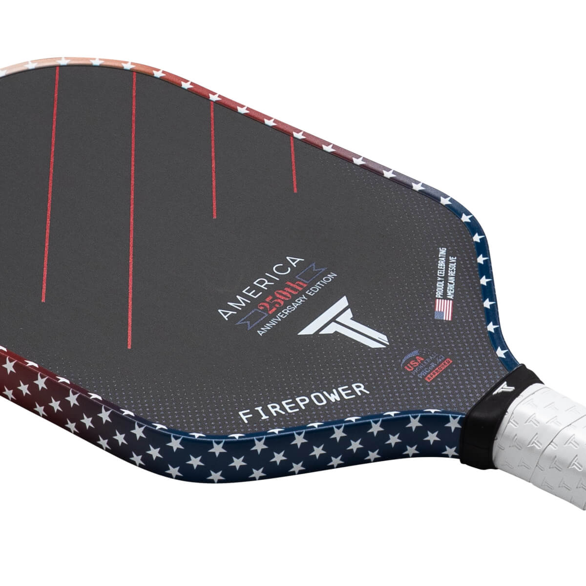 Corner view of a pickleball paddle featuring a dark surface with red stripes, "AMERICA 250th ANNIVERSARY EDITION," and a white star pattern along the edge.