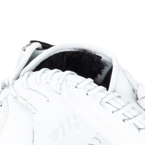 Close-up of a white leather sneaker showing black fur lining, white laces, and the word "Title" in script.