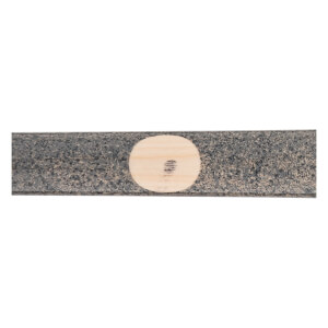 Close-up of a dark gray baseball bat with a light wood circular ink dot indicating the wood grain.