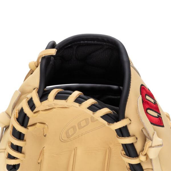 Close-up of a tan baseball glove showing black lacing and a red embroidered logo.