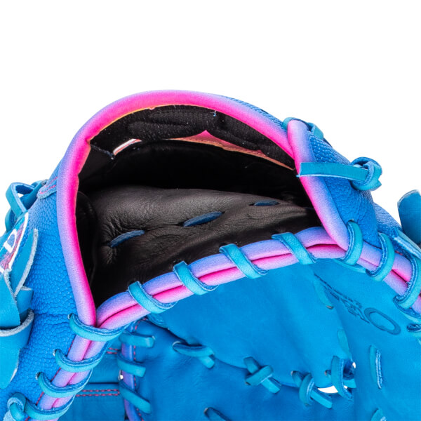 Close-up of the wrist opening and interior featuring black leather lining, neon pink gradient trim, and blue lacing on a bright blue baseball glove.