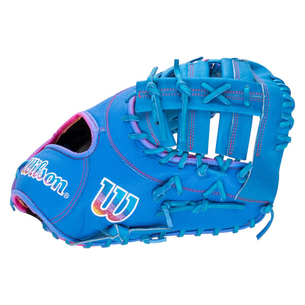 Side view of a blue pebble-textured Wilson glove featuring pink stitching and white Wilson and W logos with rainbow accents.