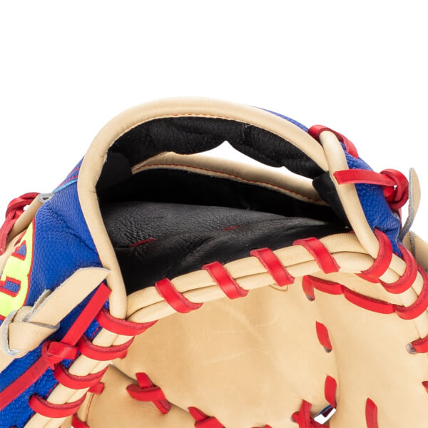 Close-up of the wrist opening on a tan and blue baseball glove featuring red lacing, a black padded interior, and a yellow Wilson logo.