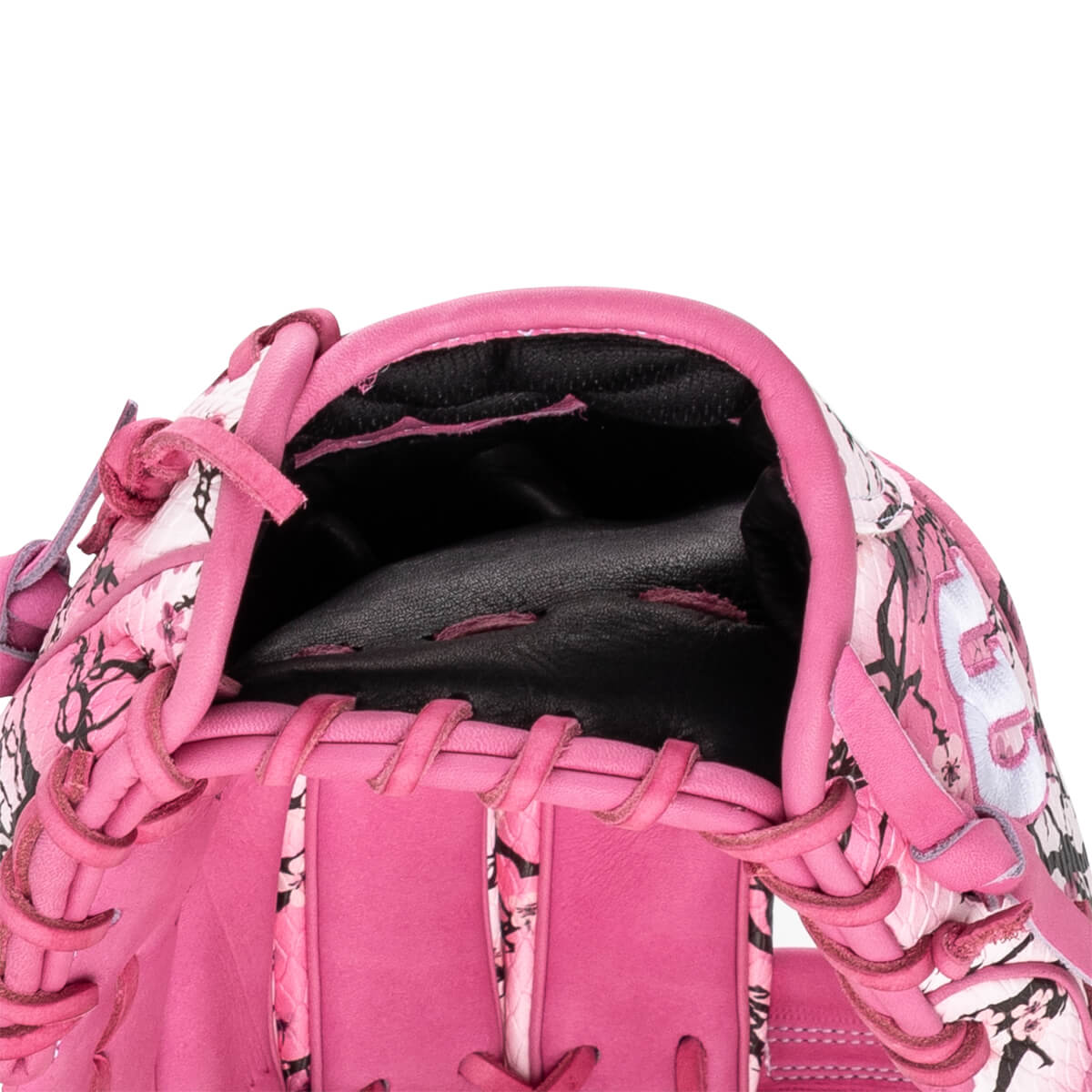 Close-up view looking into the hand opening of a pink floral baseball glove featuring black lining, pink laces, and a visible white number 8.