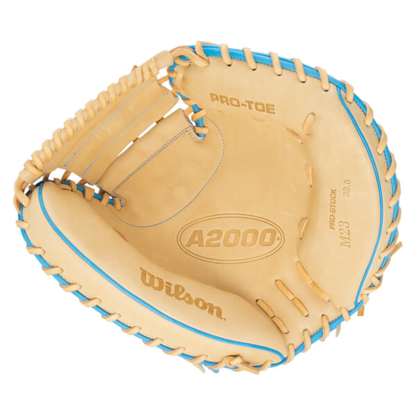 Top-down view of a tan Wilson A2000 M23 baseball glove with blue lacing and "PRO-STOCK" text.