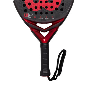 Close-up of a black and red Wilson Bela Pro padel racket with a perforated face, red throat, and black grip.