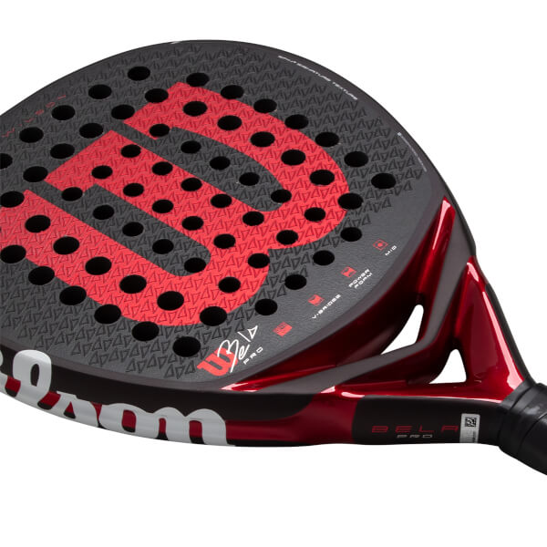 Angled close-up of a black and red padel racket with a textured face, red Wilson W logo, and Bela Pro on the throat.
