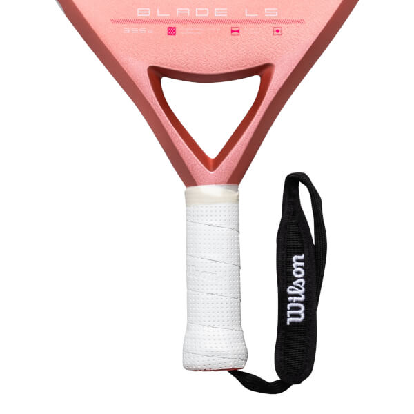Close-up of a pink pickleball paddle showing "BLADE LS" and a white grip with a black Wilson wrist strap.