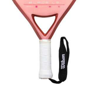 Close-up of a pink pickleball paddle showing "BLADE LS" and a white grip with a black Wilson wrist strap.