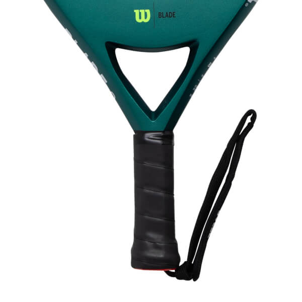 Close-up of a dark green padel racket with a black textured grip, visible W BLADE logo, and black wrist strap.