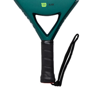 Close-up of a dark green padel racket with a black textured grip, visible W BLADE logo, and black wrist strap.