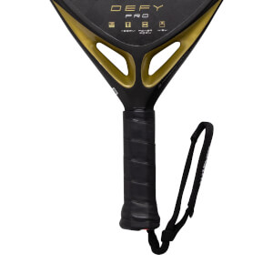 Close-up of a black and gold padel racket with a textured black grip, black wrist strap, and gold DEFY PRO branding.