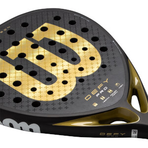 Close-up of a black and gold padel racket with a perforated surface, large gold W logo, and DEFY PRO text.
