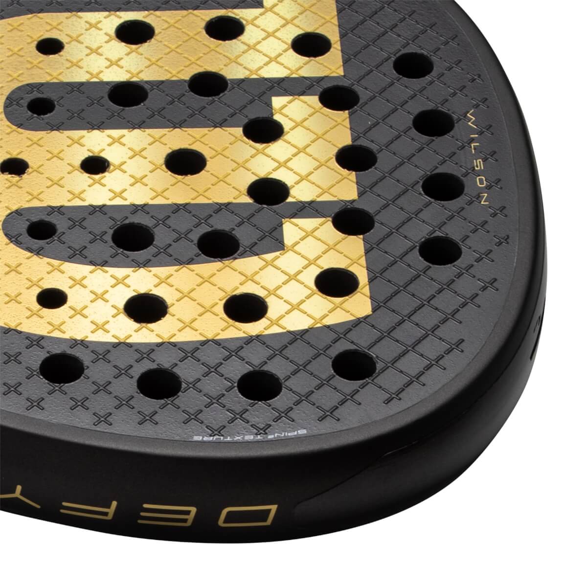 Close-up of a black and gold padel racket with a textured face, round holes, and WILSON and DEFY branding.