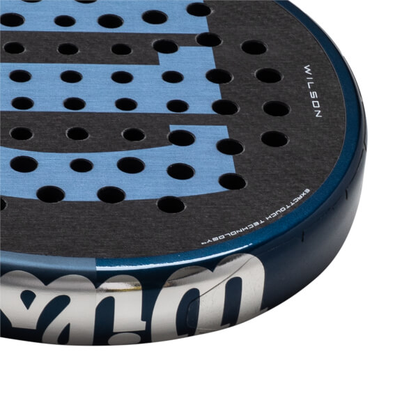 Corner view of a dark blue padel racket with a black and light blue patterned hitting surface and "WILSON" text.
